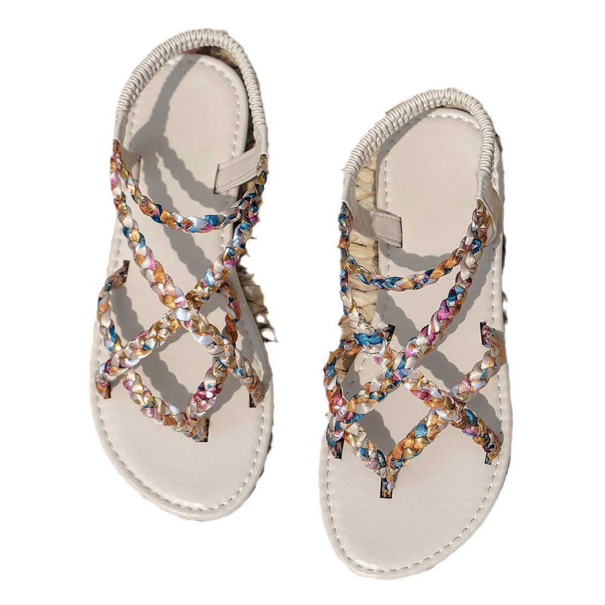 A pair of flat, low-top sandals with a cloth upper and elastic band closure across the instep.