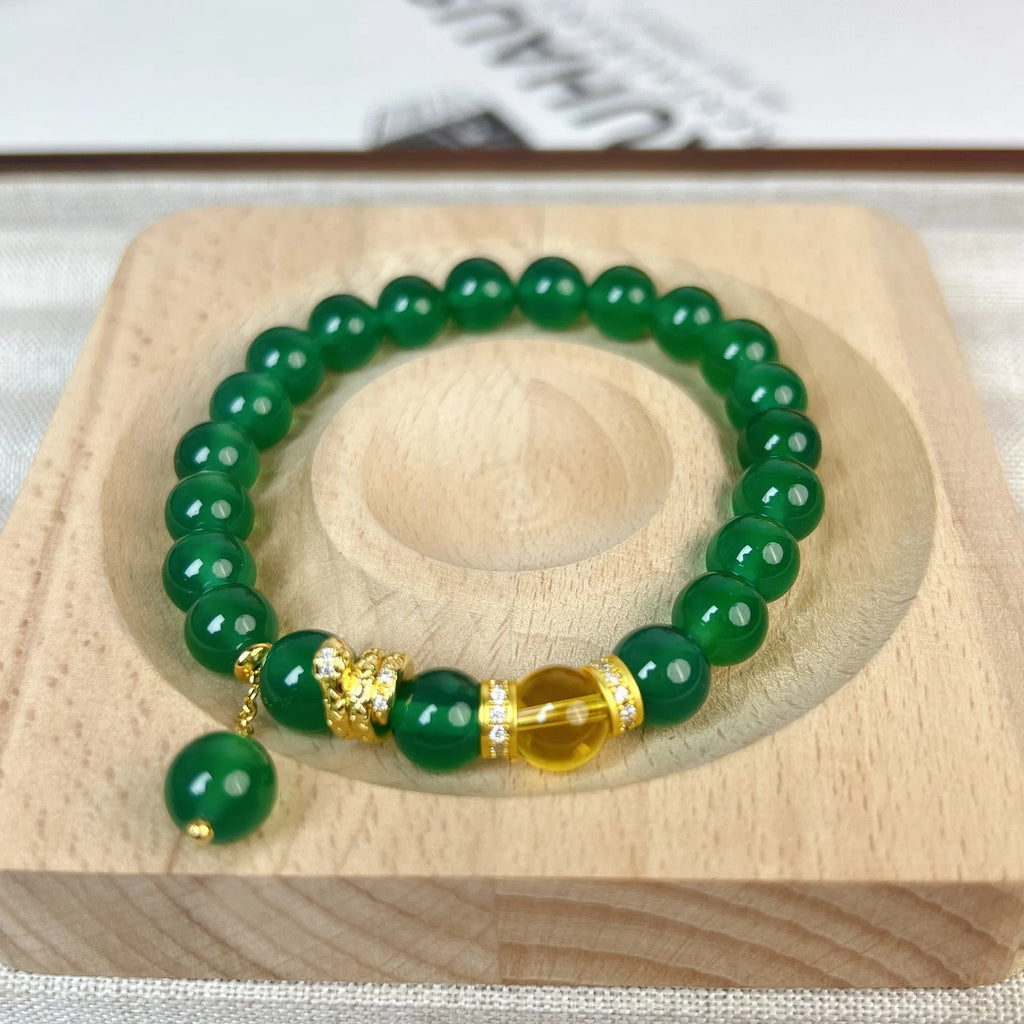Green and red agate stone bead wealth snake bracelet with copper details on a wrist.