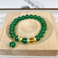 Green and red agate stone bead wealth snake bracelet with copper details on a wrist.