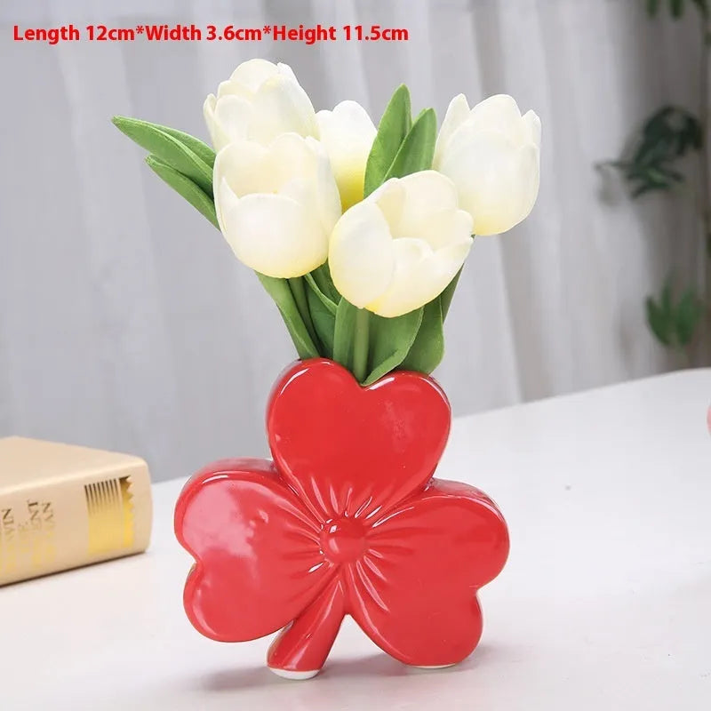 White porcelain clover-shaped ceramic vase on a desk, shown in light green colour.