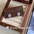 S925 sterling silver earrings with geometric heart-wrapped design and oval blue diamond elements