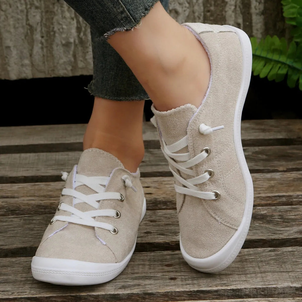 Women's creamy white low-top fabric casual sneakers with a rubber sole on a neutral background.