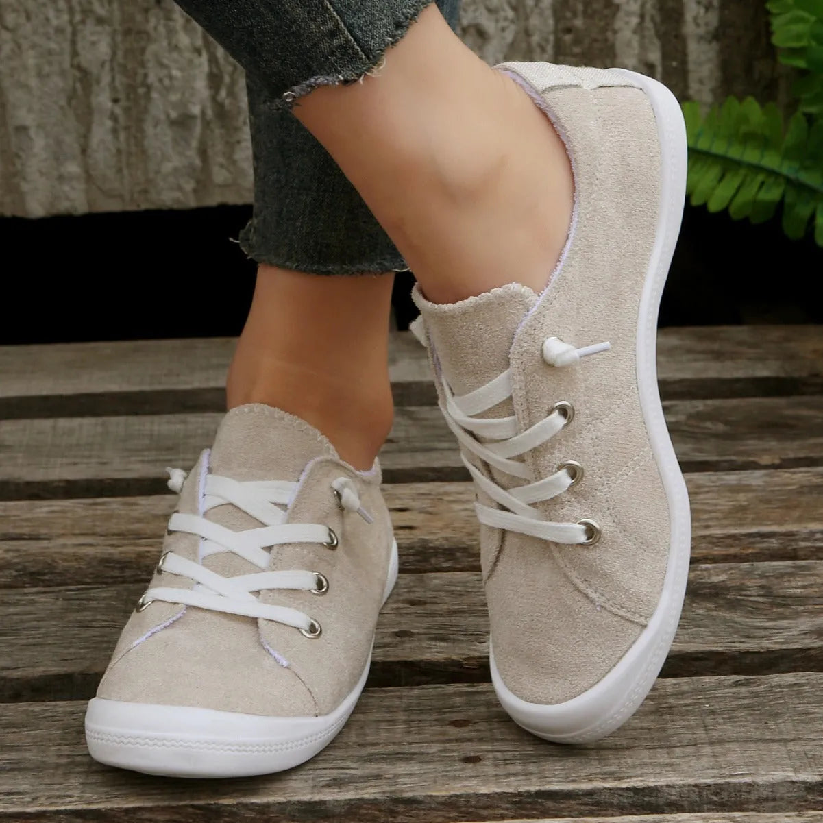 Women's creamy white low-top fabric casual sneakers with a rubber sole on a neutral background.