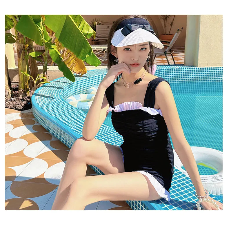 Women's solid colour one-piece swimsuit with suspender straps in black, pink, or green.