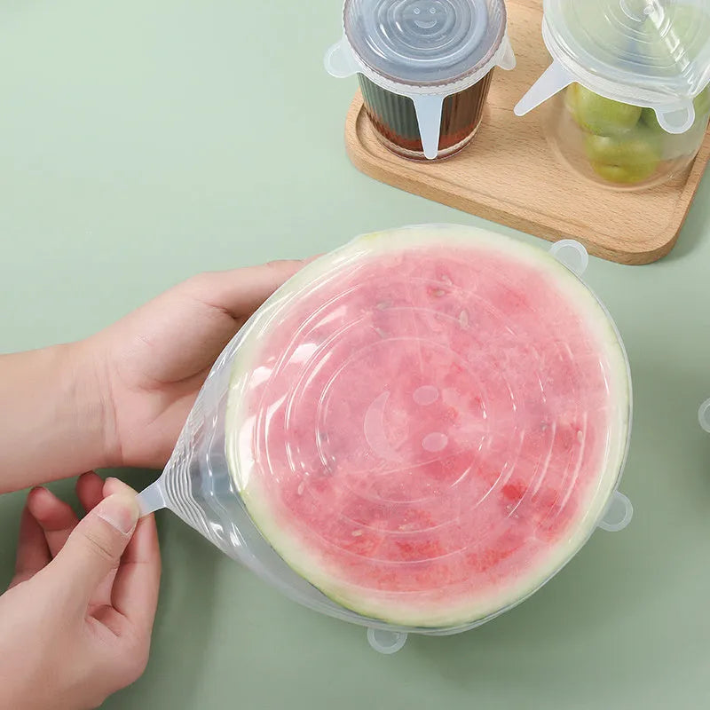 Set of six colourful silicone stretch food covers in different sizes on a kitchen counter.