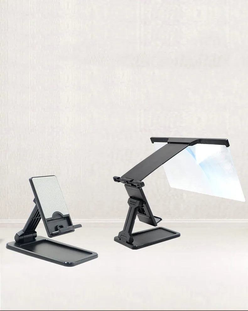 Black detachable mobile phone screen amplifier and folding holder shown on a desk next to a phone.