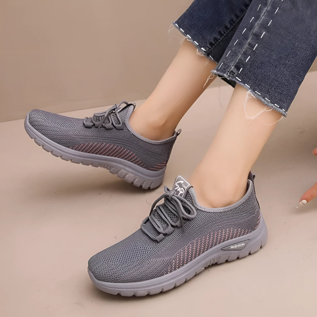 Women's black casual sneakers with mesh upper, cross straps, and round toe on a rubber sole.