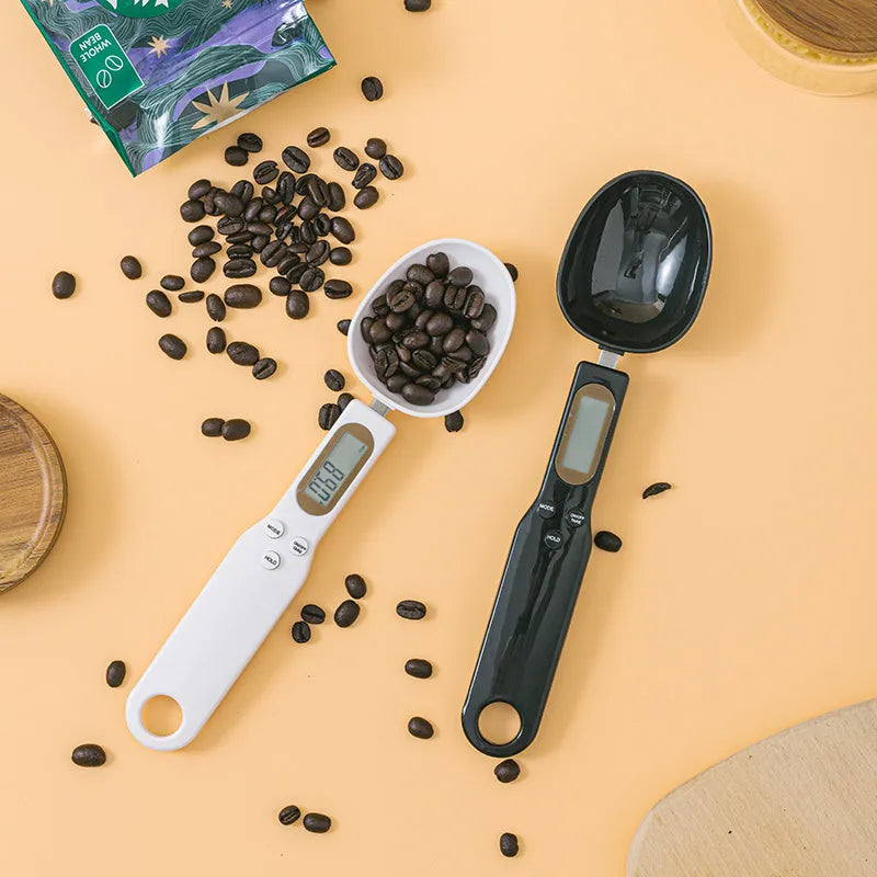 White electronic digital spoon scale with LCD display on a kitchen counter.