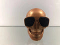 Small skull-shaped wireless Bluetooth speaker in black, portable with button controls and USB charging