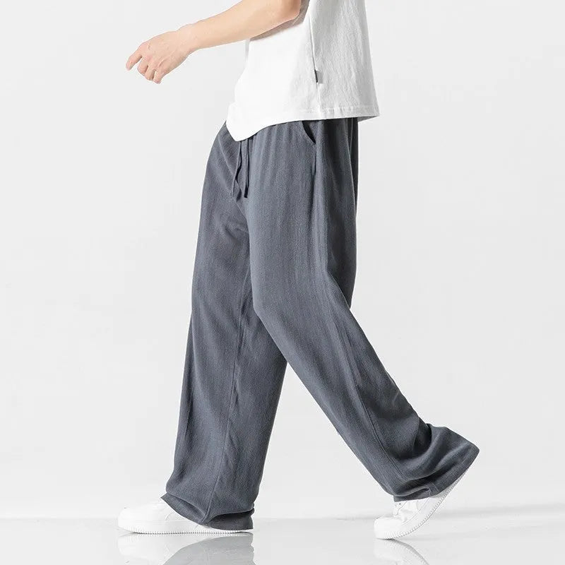 Man wearing beige straight-leg cropped linen-style trousers with a drawstring waist.