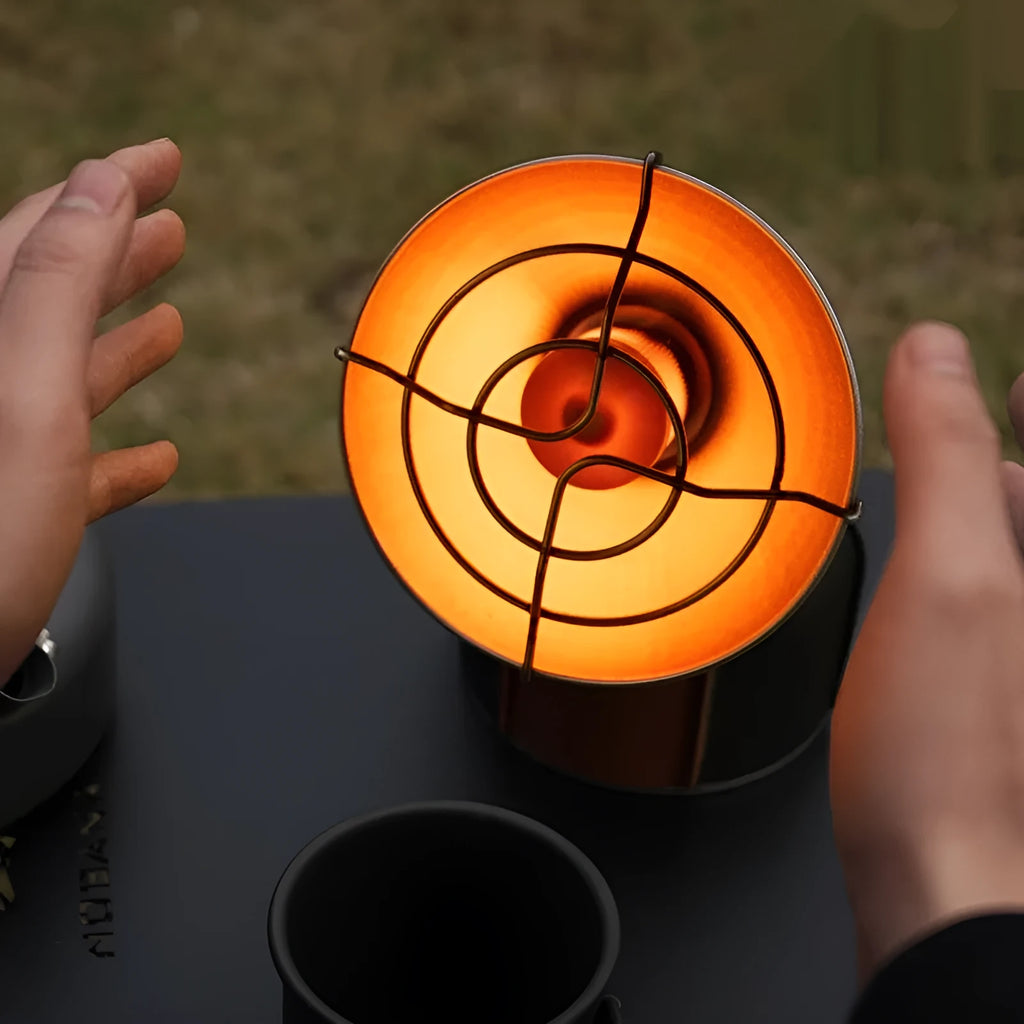 Black and orange portable outdoor camping heater stove with automatic ignition on a table.