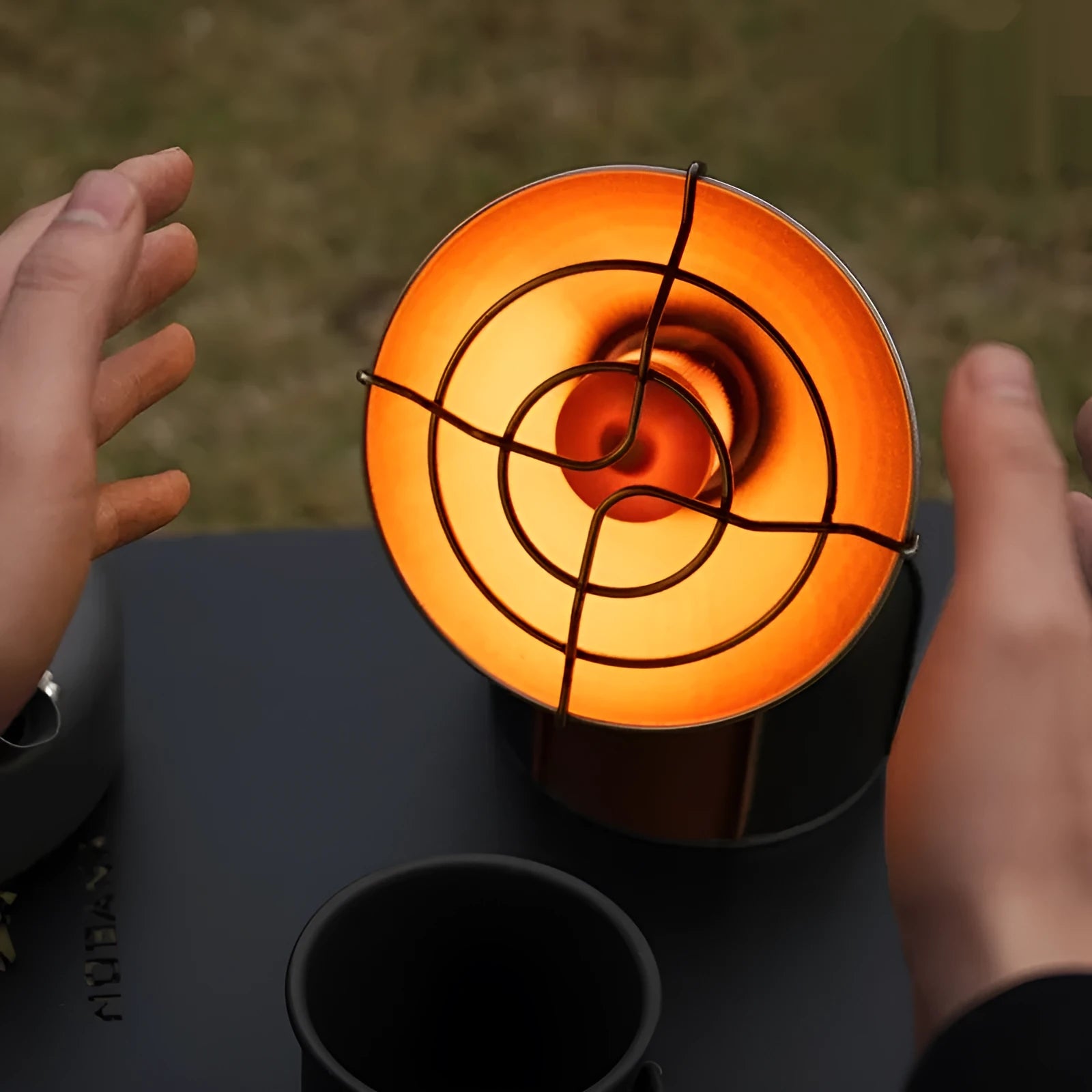 Black and orange portable outdoor camping heater stove with automatic ignition on a table.