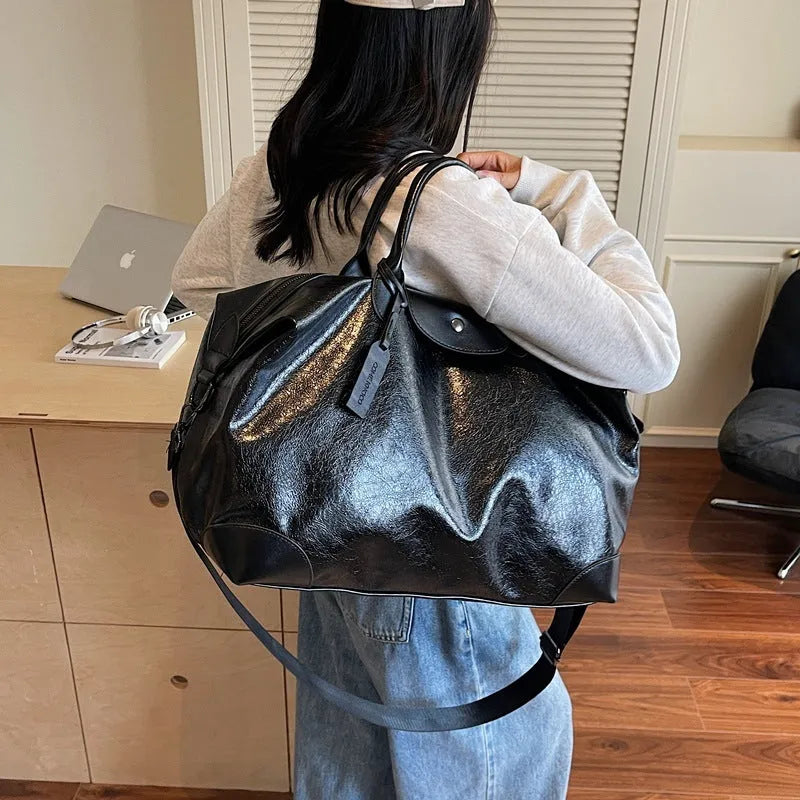 Women's hand-carrying travel bag in black or silver with 36-55L capacity