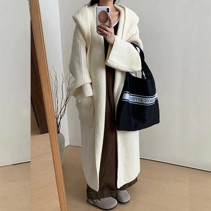 Woman wearing a loose beige hooded zip-front cardigan coat with raglan sleeves.