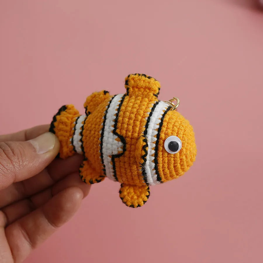 Crocheted wool fish keychain in cartoon ugly fish doll style with key ring, shown in orange, blue or pink