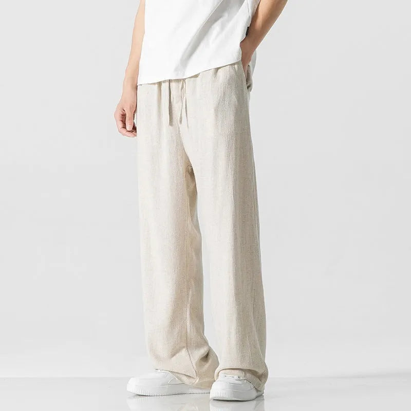 Man wearing beige straight-leg cropped linen-style trousers with a drawstring waist.