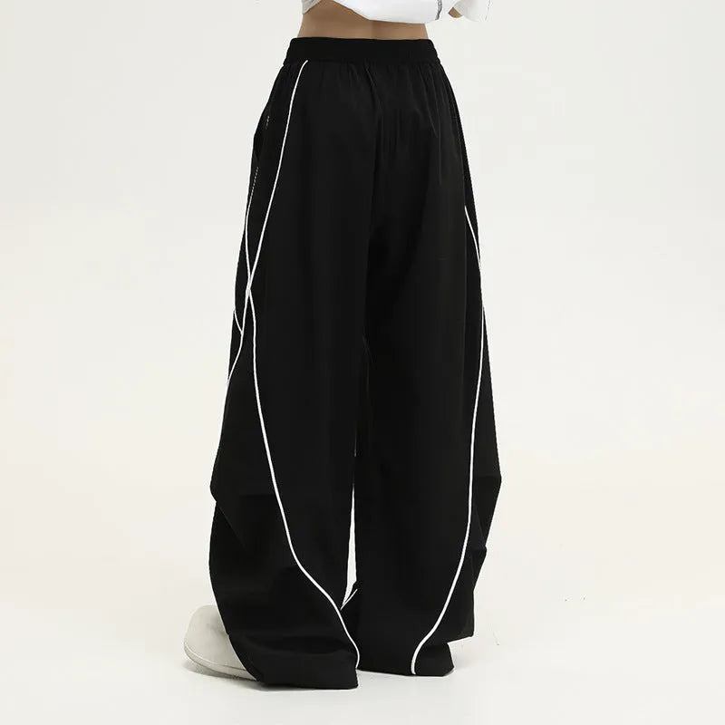 Black striped wide-leg sports pants with pleated detail on a mid-waist, loose fit.