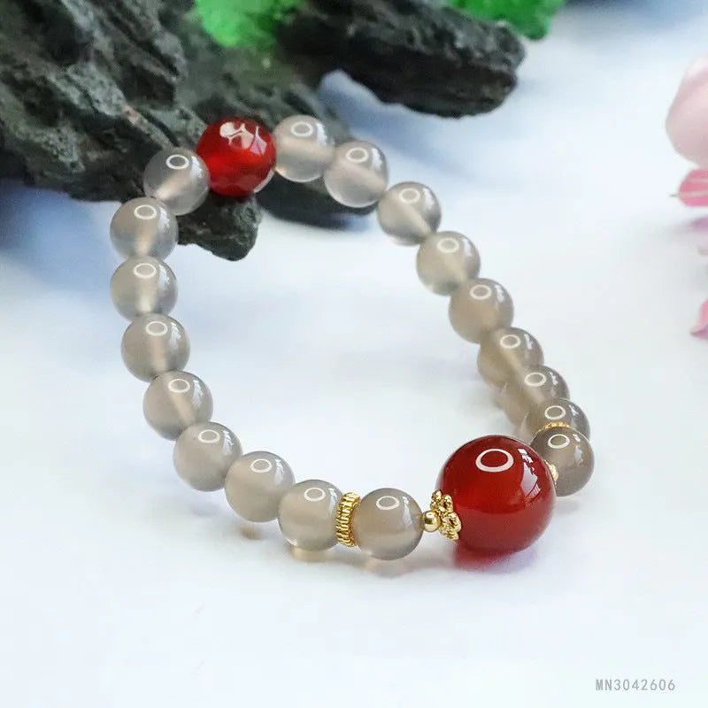 Close-up of a bracelet with smoky purple and red agate geometric beads on a white background.