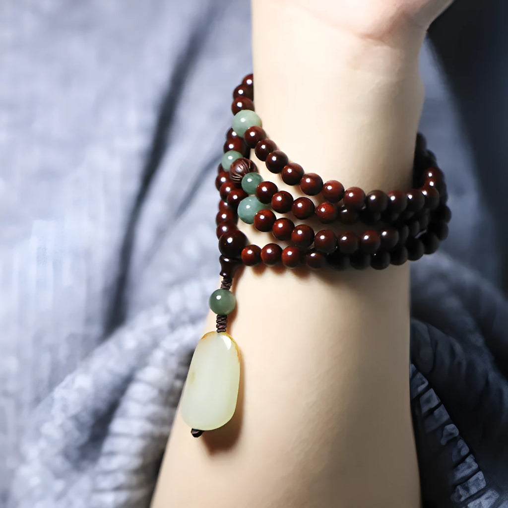 Carved rosewood bead bracelet with Hotian jade pendant showing wood grain texture
