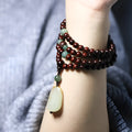 Carved rosewood bead bracelet with Hotian jade pendant showing wood grain texture