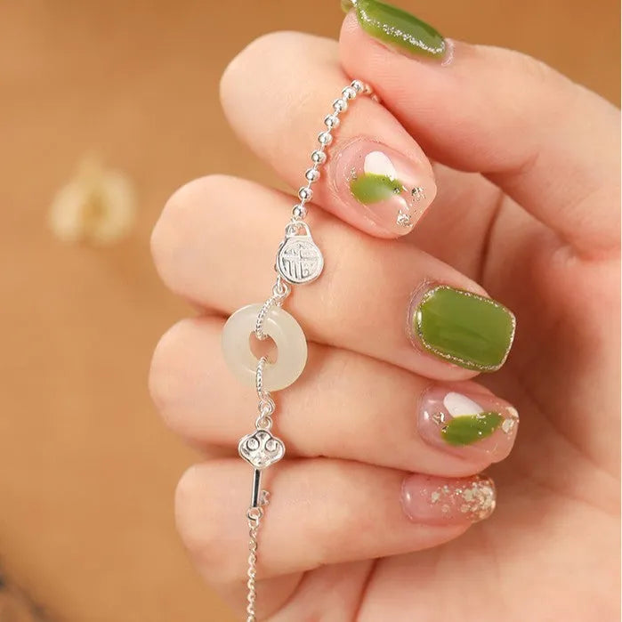Women's silver bracelet with Hetian jade and a traditional Chinese peace buckle charm on a geometric link chain.