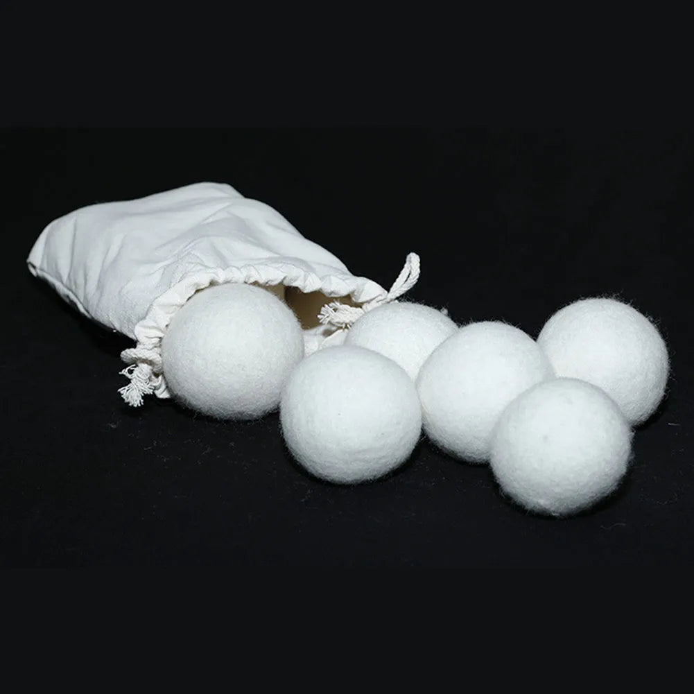 Handmade natural wool felt drying ball for laundry next to a plain cotton storage bag.