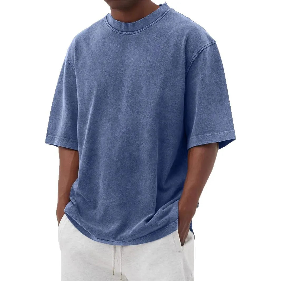 Man wearing a loose fit stone washed distressed t-shirt in a solid colour, showing short sleeves and casual styling.