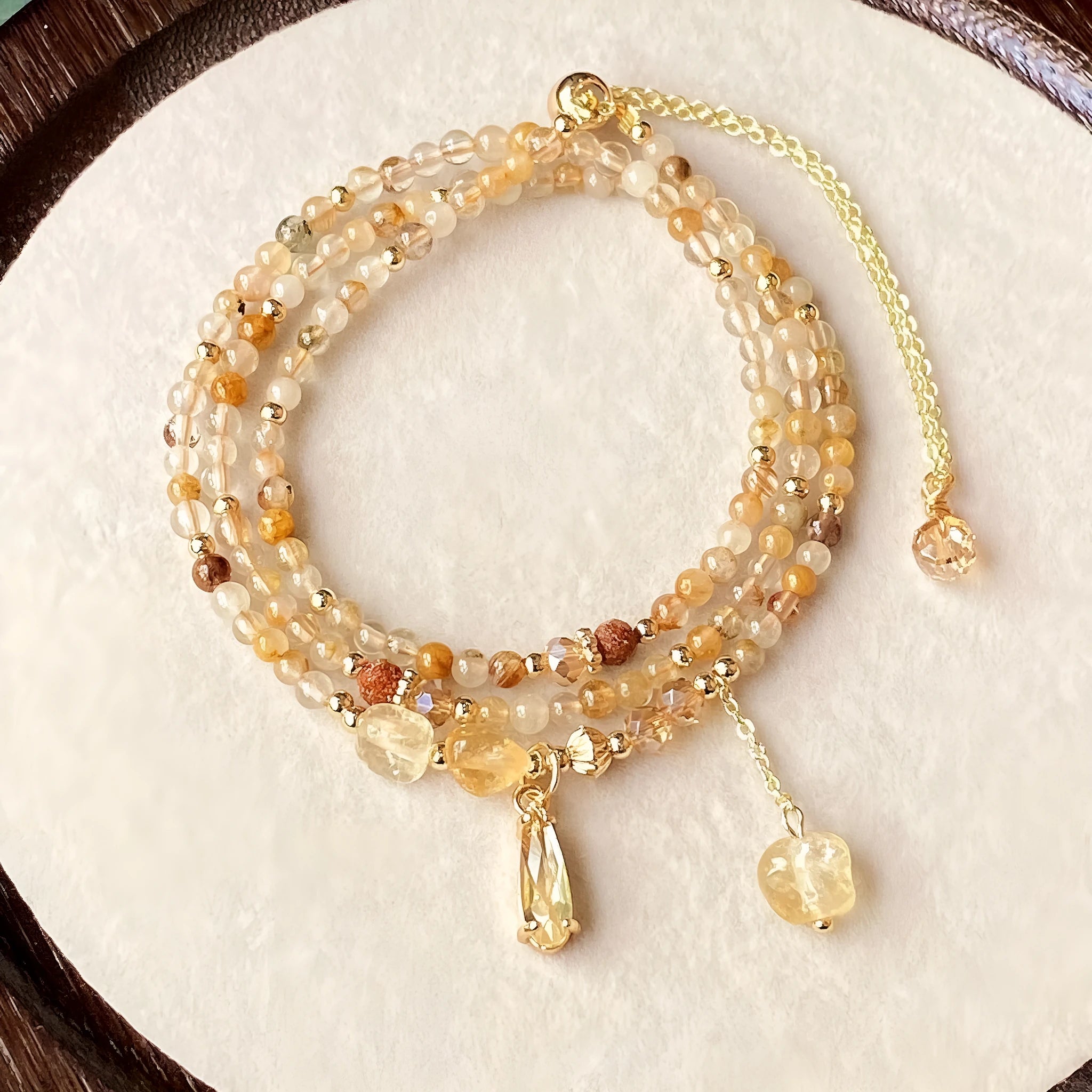 Gold electroplated bracelet with three circles of caramel citrine and a Saturn charm.