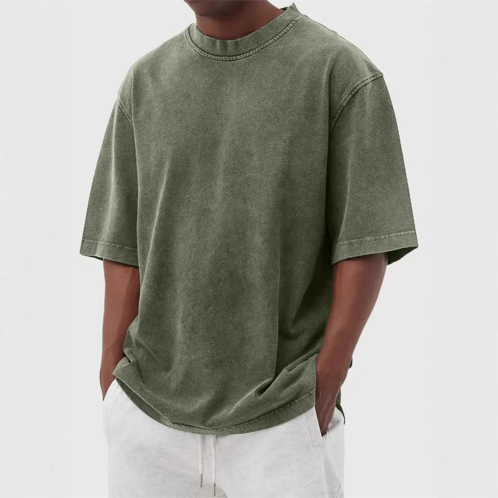 Man wearing a loose fit stone washed distressed t-shirt in a solid colour, showing short sleeves and casual styling.