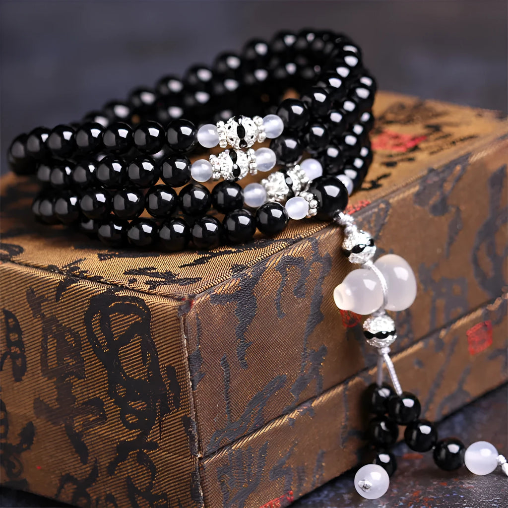 Black agate bracelet with 108 geometric beads on a wrist.