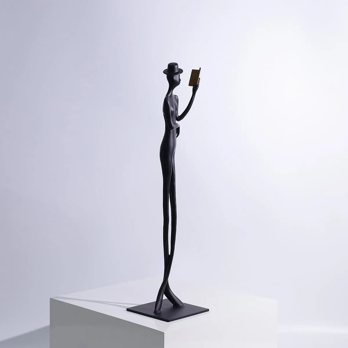 Black cast aluminium desktop sculpture of reading woman measuring 12x12x51cm