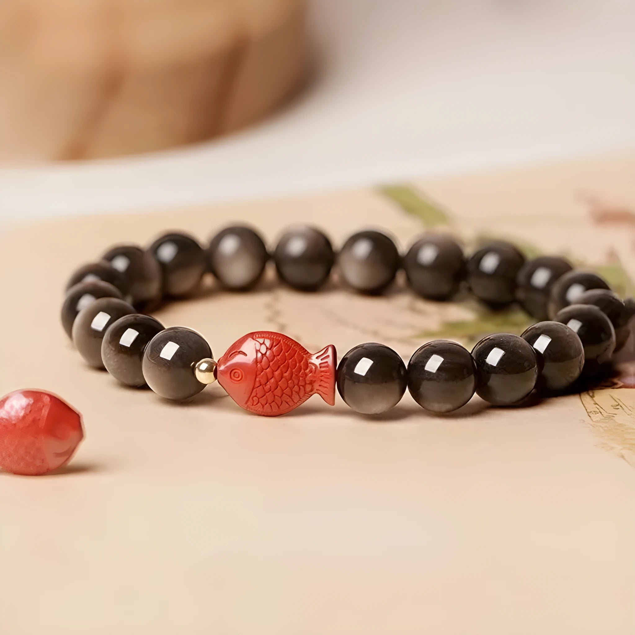 Natural obsidian round bead bracelet with a red cinnabar fungus charm, showing different bead size options.