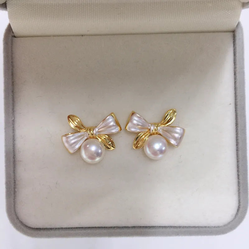 Two-tone bow pearl stud earrings in white or gray with flat circle shape