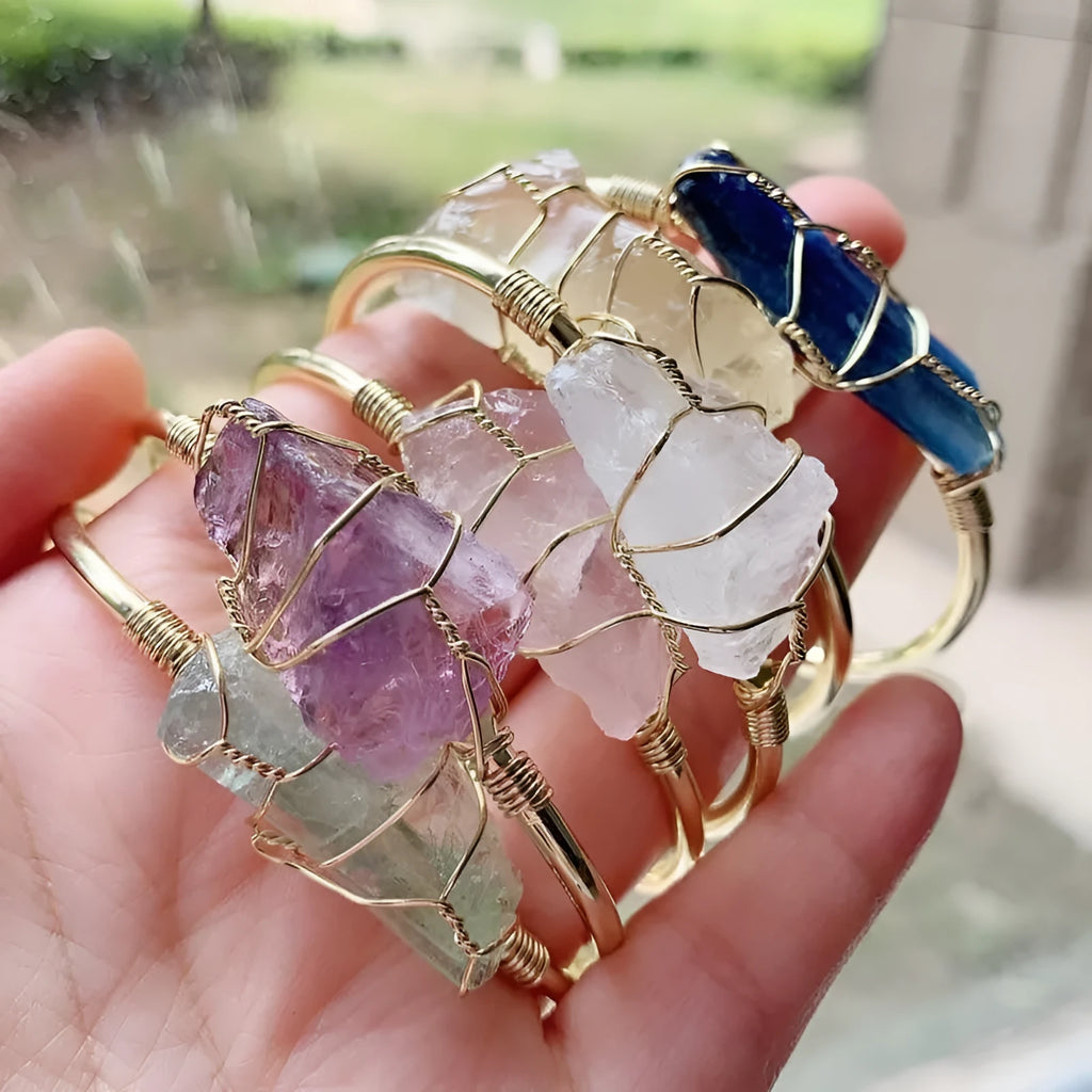 Natural rough stone crystal bracelet with gold geometric winding on a wrist.