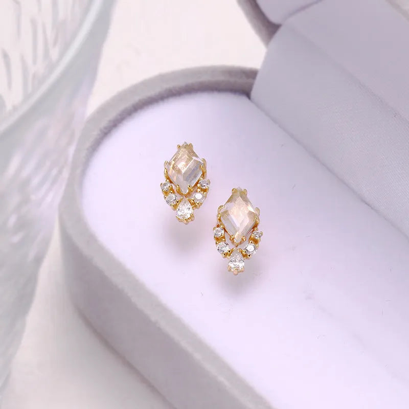 A pair of geometric sterling silver earrings with sweet white crystal studs on a white background.