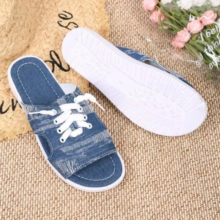 Blue women's flat canvas slippers with cloth lining and a rubber sole, shown in Roman style.