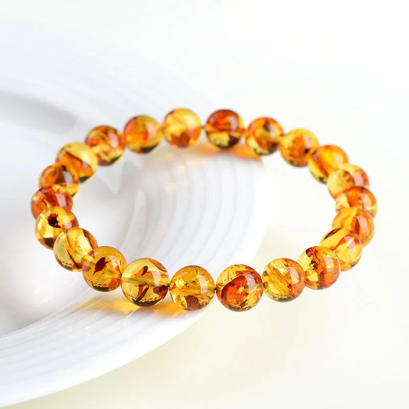 Natural yellow piebald amber geometric bracelet on a wrist, showing polished beads with flower spot patterning.