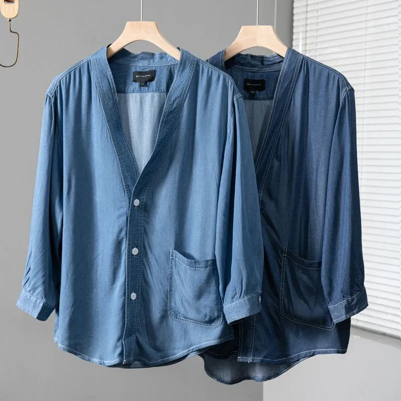 Men's dark blue V-neck denim coat with three-quarter sleeves showing loose fit and pocket detail