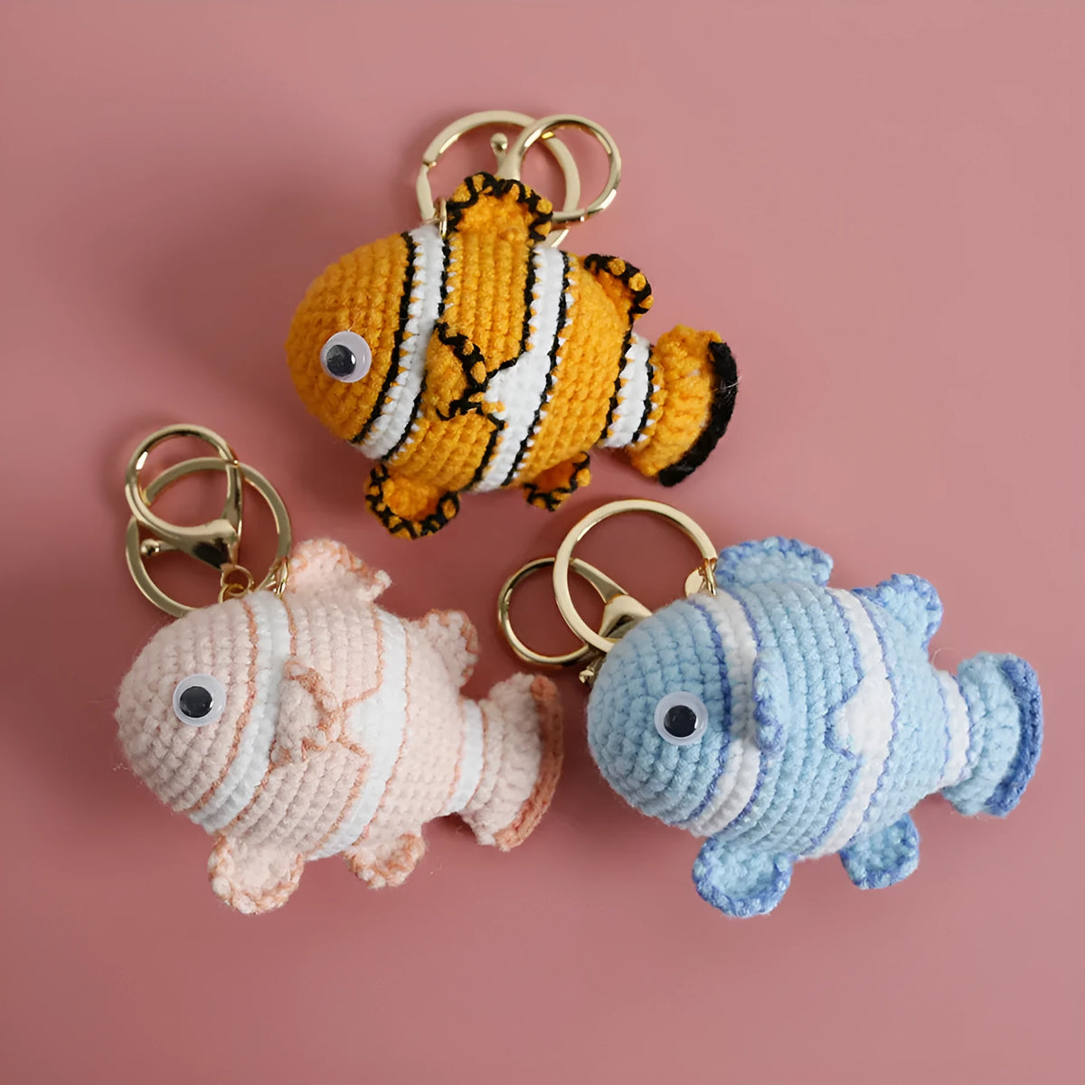 Crocheted wool fish keychain in cartoon ugly fish doll style with key ring, shown in orange, blue or pink