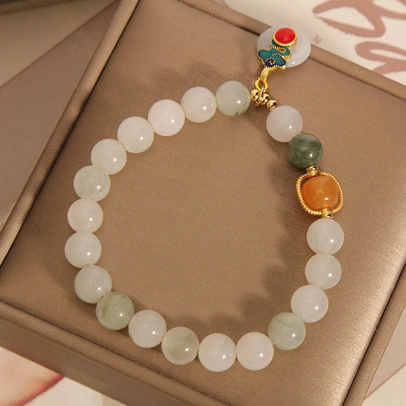 Women's ice jade bracelet with xiangyun pattern, peace buckle, and pearl accents on a white background.