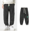Men's loose-fit tapered cotton trousers in mid-waist design, shown in black colour.