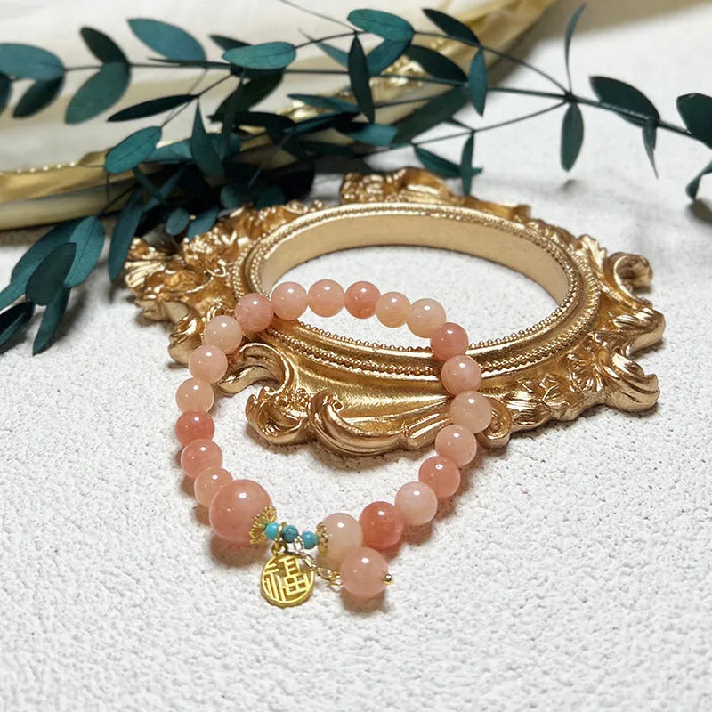 Close-up of a pink natural stone set within a simple silver-toned alloy women's bracelet.