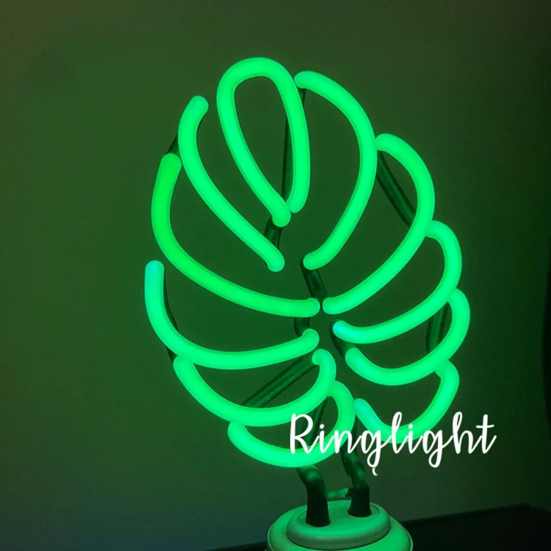 Minimalist white bamboo-shaped desk lamp emitting a soft green light, shown on a table.