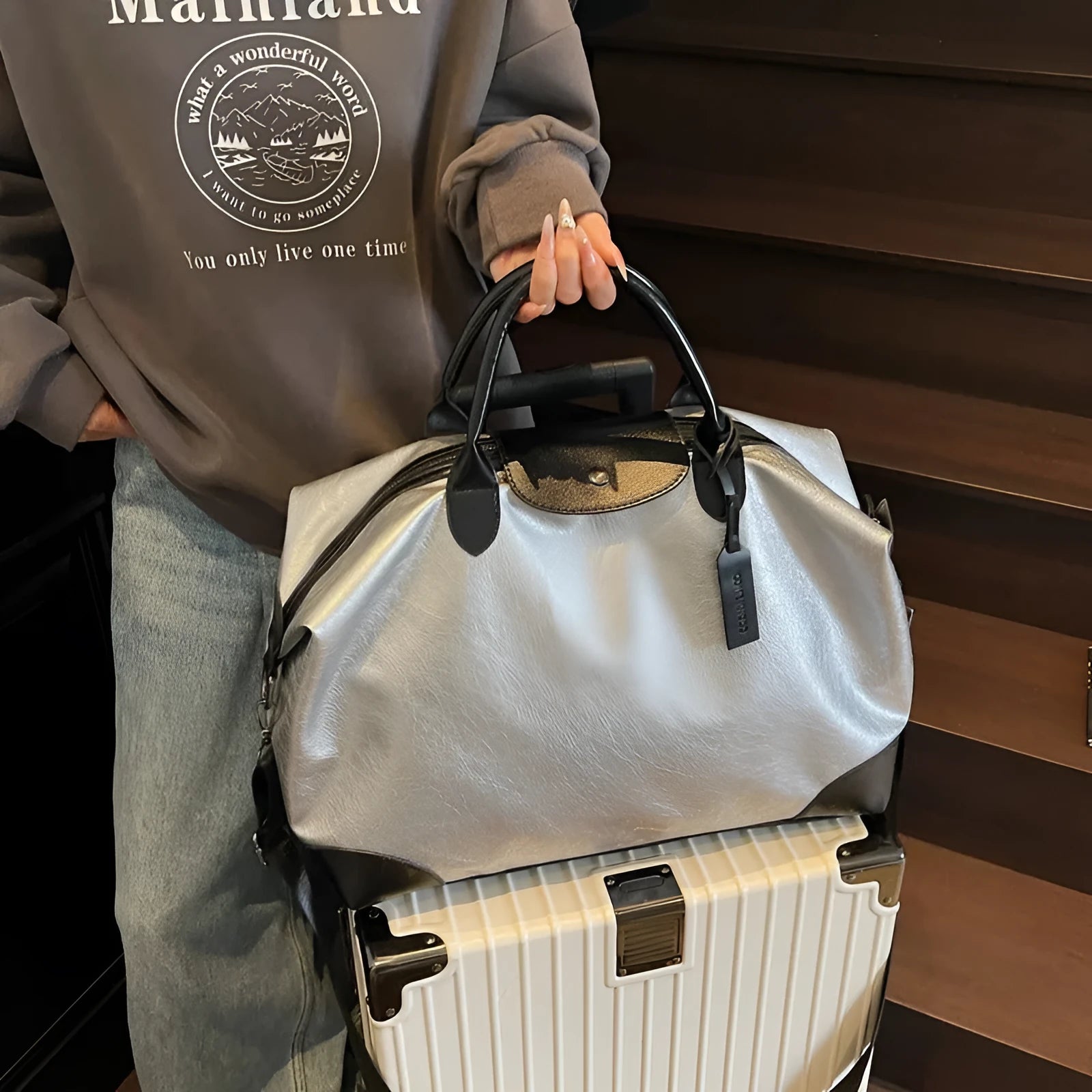 Women's hand-carrying travel bag in black or silver with 36-55L capacity