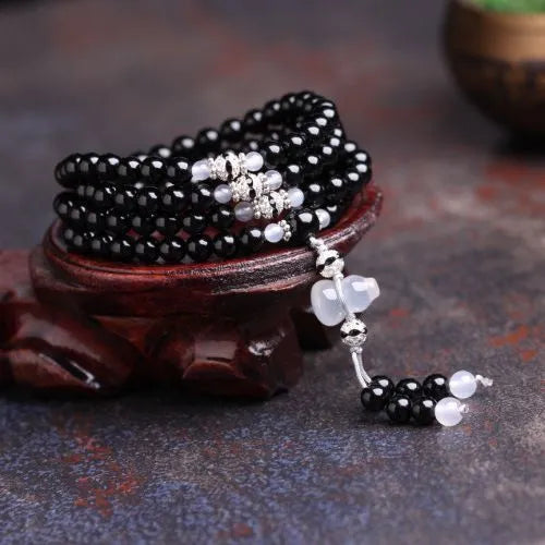 Black agate bracelet with 108 geometric beads on a wrist.