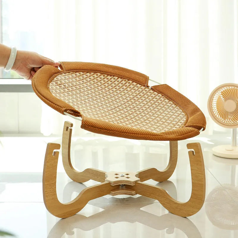 Brown woven rattan raised cot bed for cats and small dogs on a wooden floor