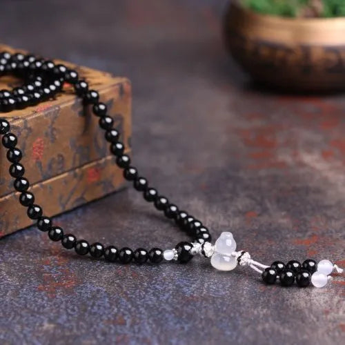 Black agate bracelet with 108 geometric beads on a wrist.