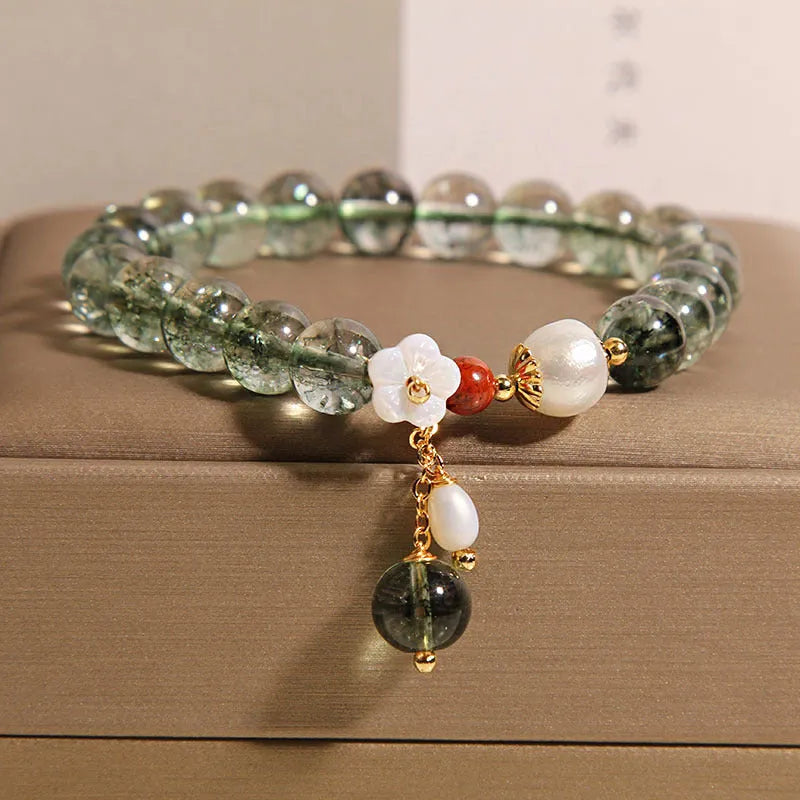 Green phantom quartz crystal bracelet with shell flower charms on wrist
