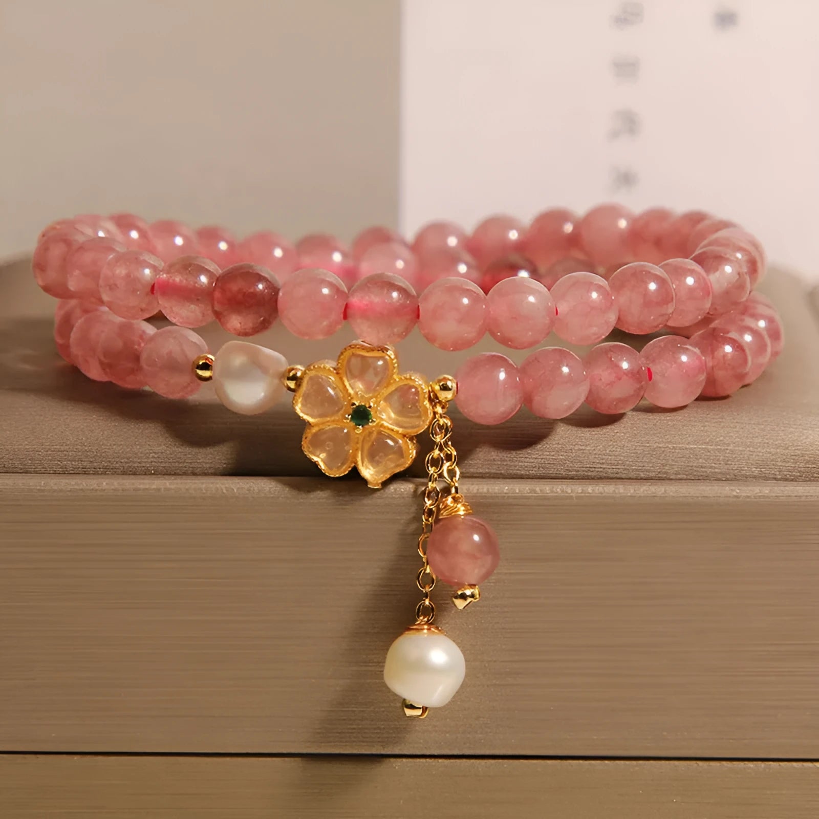 Close-up of a women's bracelet with a strawberry quartz four-leaf clover charm on an alloy chain.