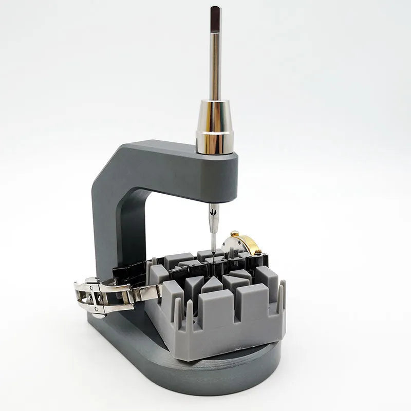 Silver tool steel press strap removal tool for watch and jewellery repair on a workbench.